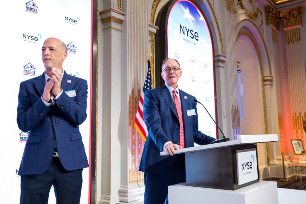 two men in blue suits at a podium